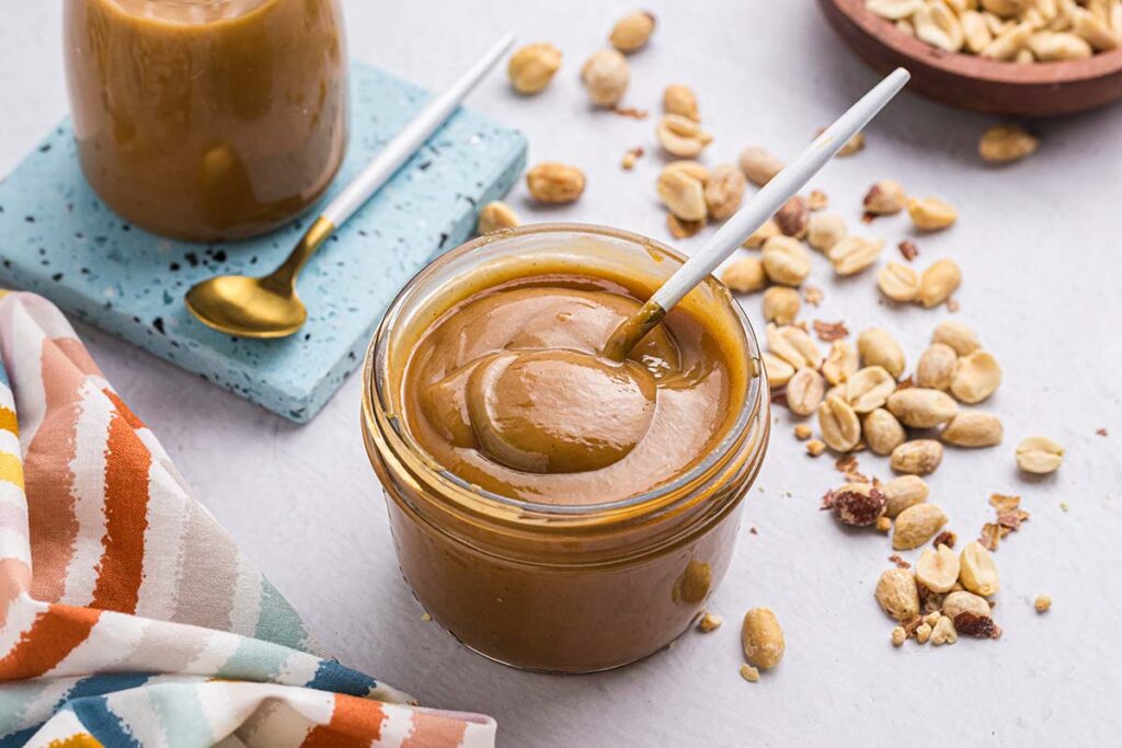angled shot of spoon in jar of peanut butter sauce