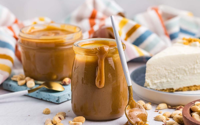 spoon leaning against jar of peanut butter sauce