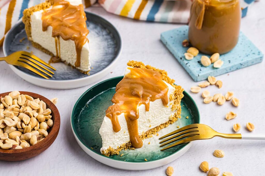 angled shot of two slices of cheesecake drizzled with peanut butter sauce