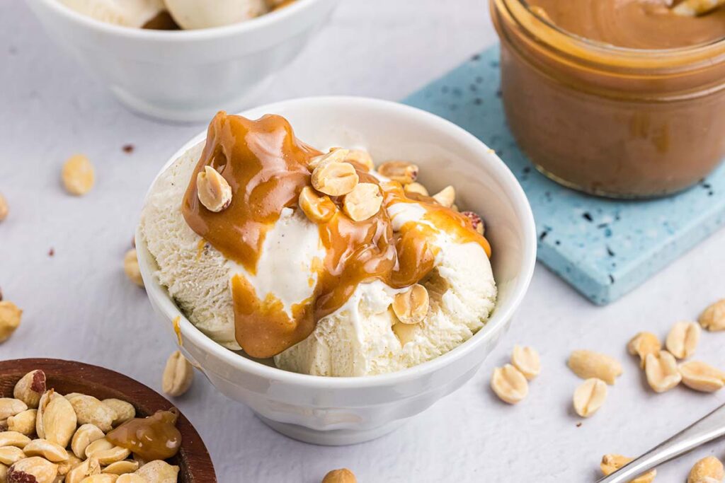 close up angled shot of bowl of ice cream topped with peanut butter sauce