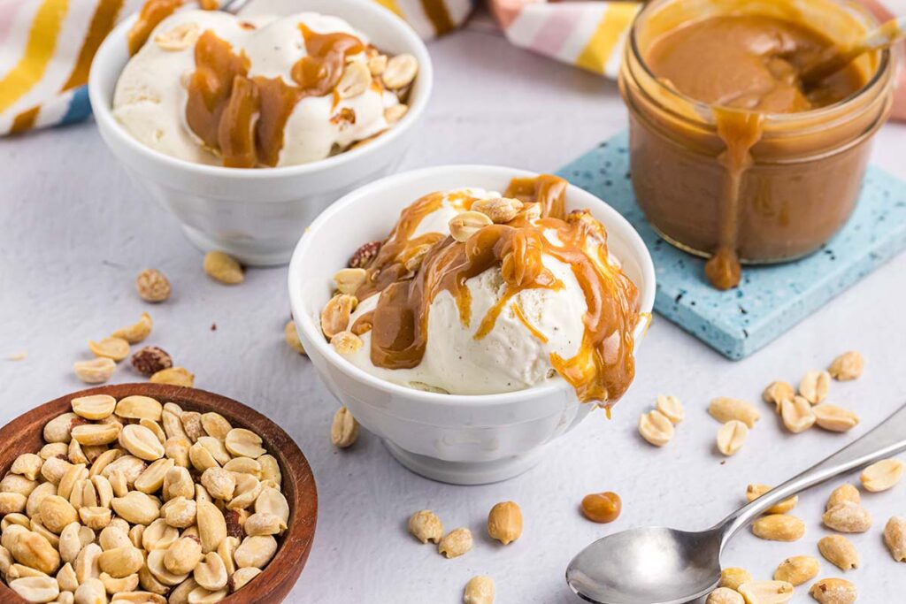 angled shot of two bowls of ice cream topped with peanut butter sauce