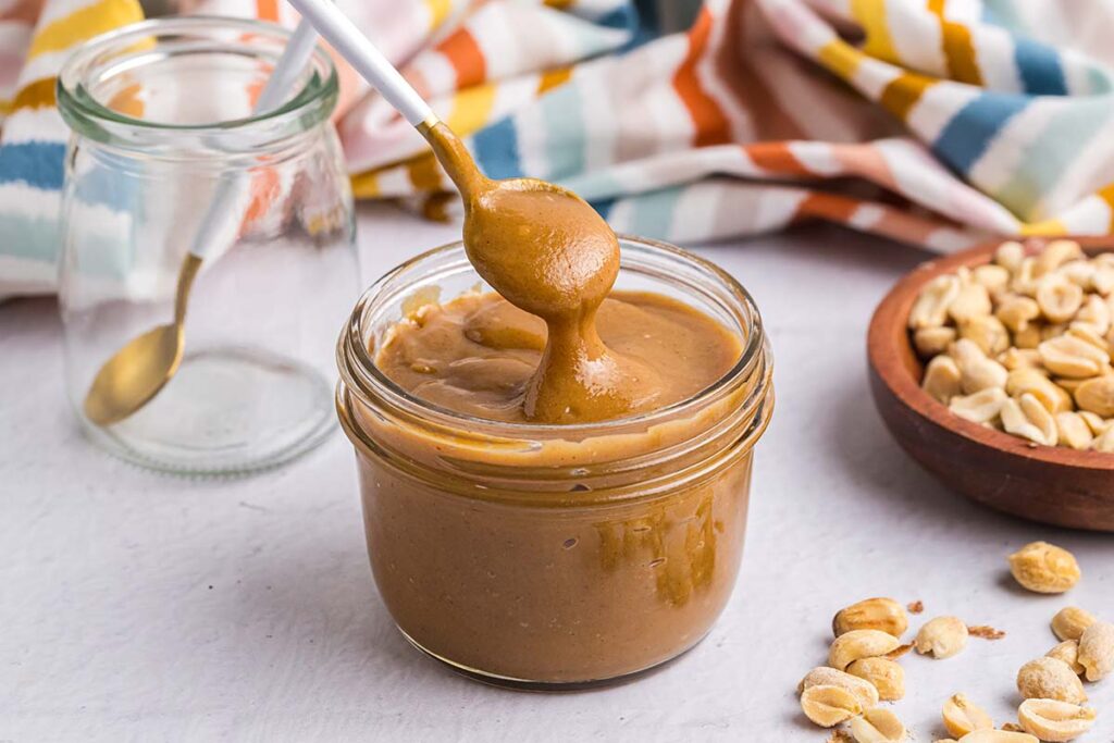spoon dipping into jar of peanut butter sauce