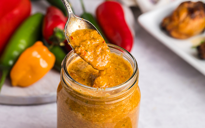 spoon dipping into jar of peri peri sauce