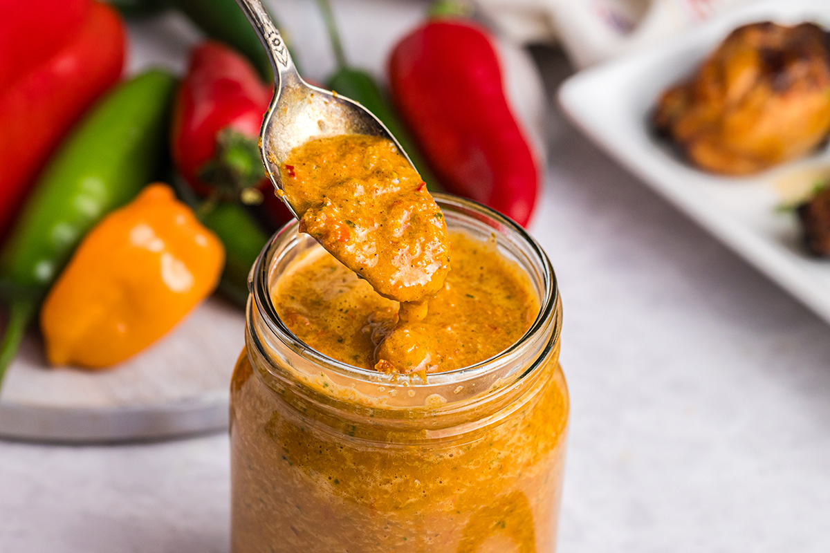 spoon dipping into jar of peri peri sauce