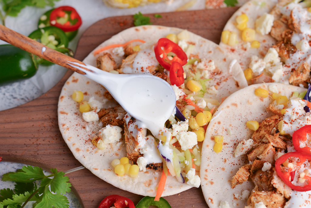 angled shot of spoon adding mexican sour cream to tacos