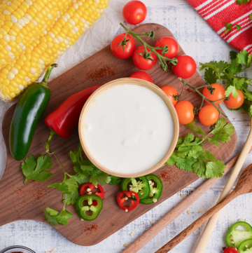 overhead shot of bowl of mexican crema on wooden board