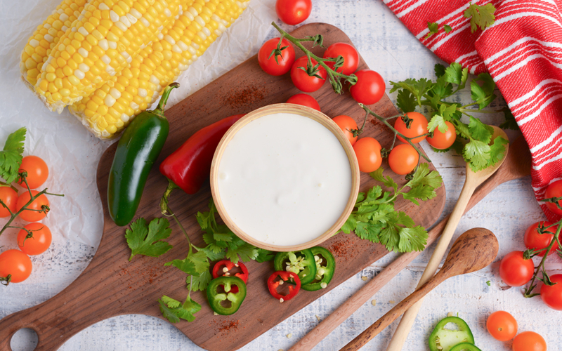 overhead shot of bowl of mexican crema on wooden board