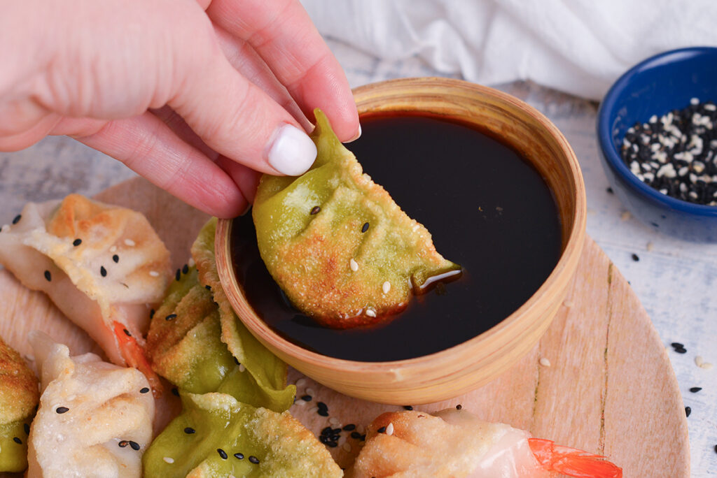 hand dipping dumpling into homemade ponzu sauce