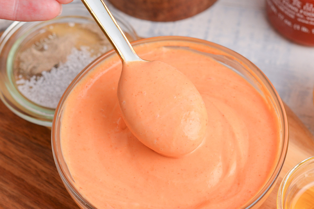 close up angled shot of spoon in bowl of sriracha mayo