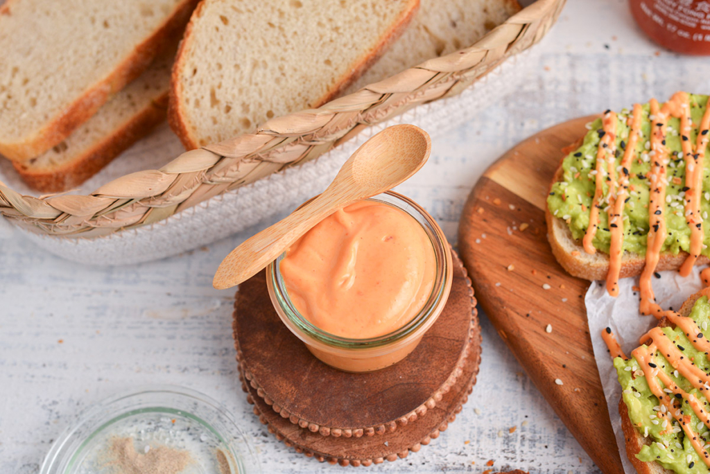 angled shot of jar of sriracha mayo with wooden spoon