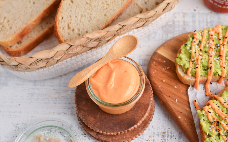 angled shot of jar of sriracha mayo with wooden spoon