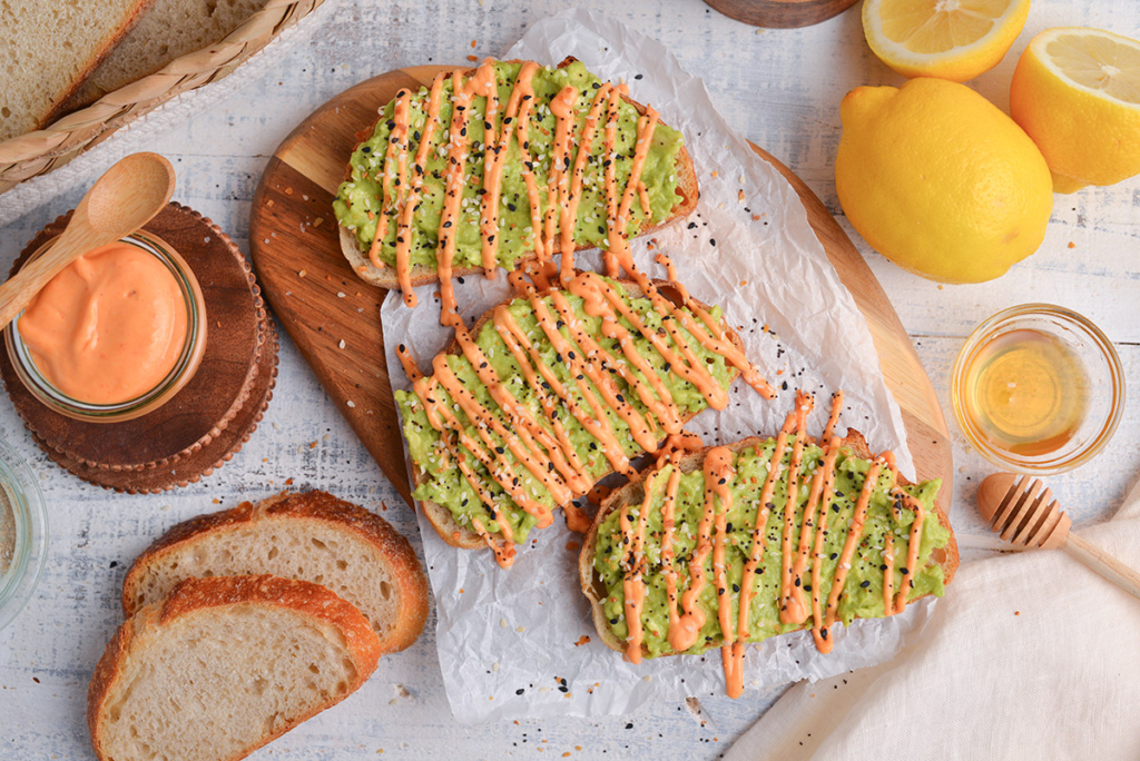 overhead shot of three pieces of avocado toast drizzle with sriracha mayo