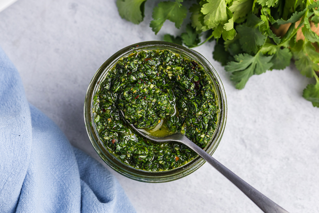 overhead shot of spoon in jar of chimichurri sauce