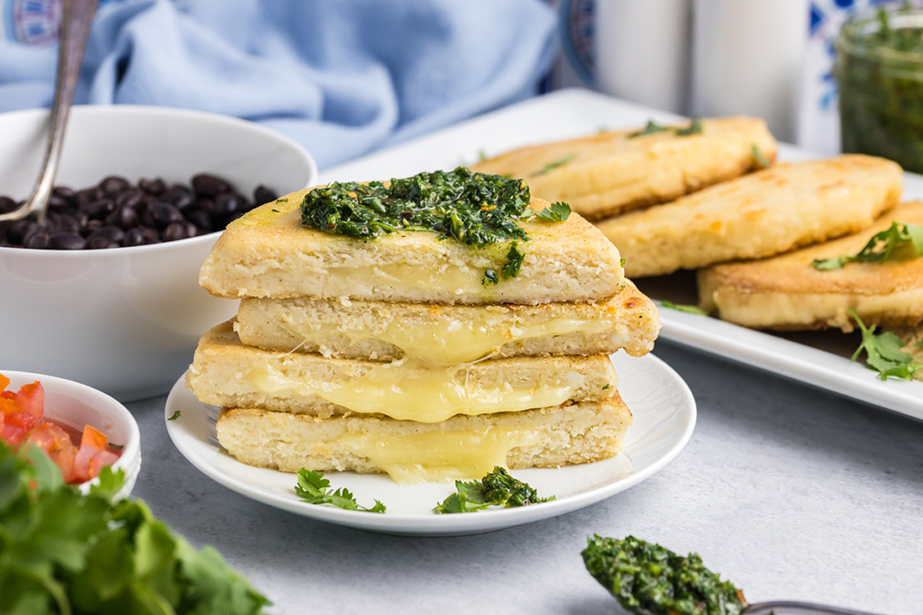 stack of arepas cut in half topped with sauce