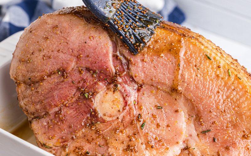 brushing basting glaze onto sliced ham