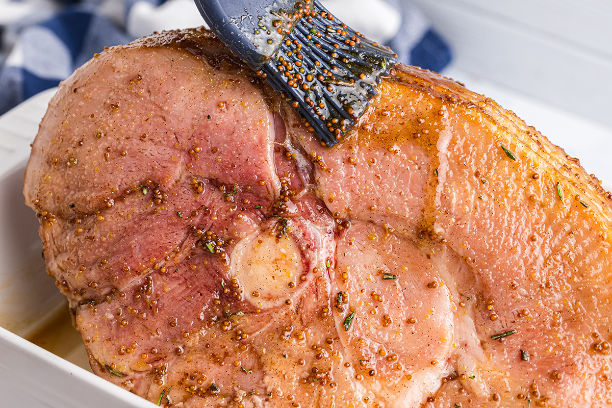 brushing basting glaze onto sliced ham