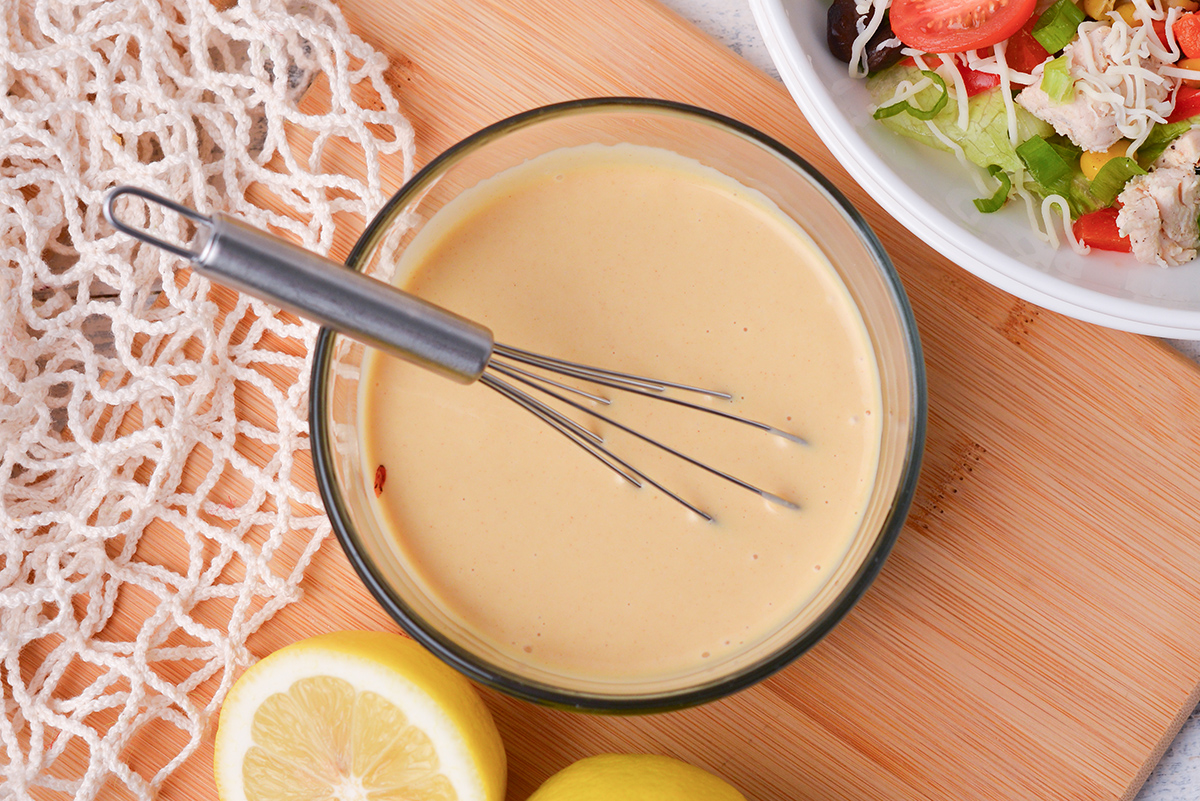 close up overhead shot of whisk in bowl of honey mustard dressing