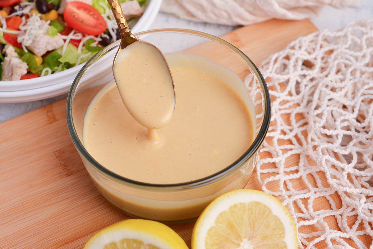 angled shot of spoon in bowl of honey mustard dressing