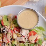 angled shot of ramekin on dressing in bowl of salad