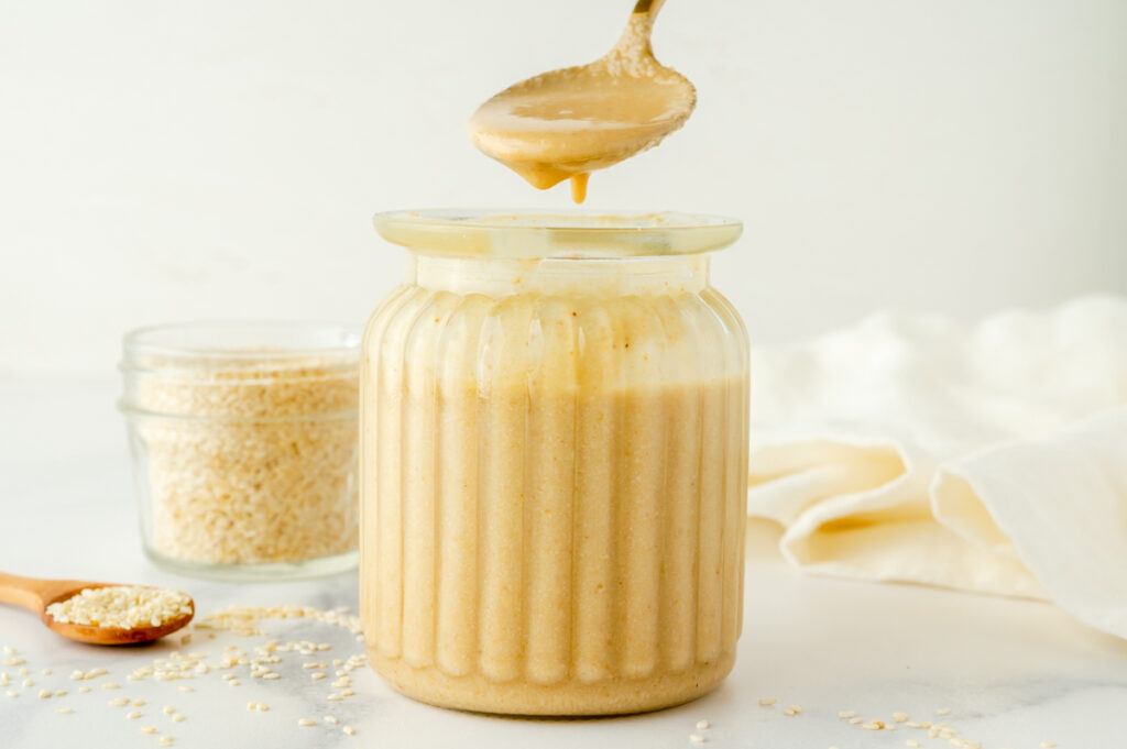 straight on shot of spoon dipping into jar of tahini