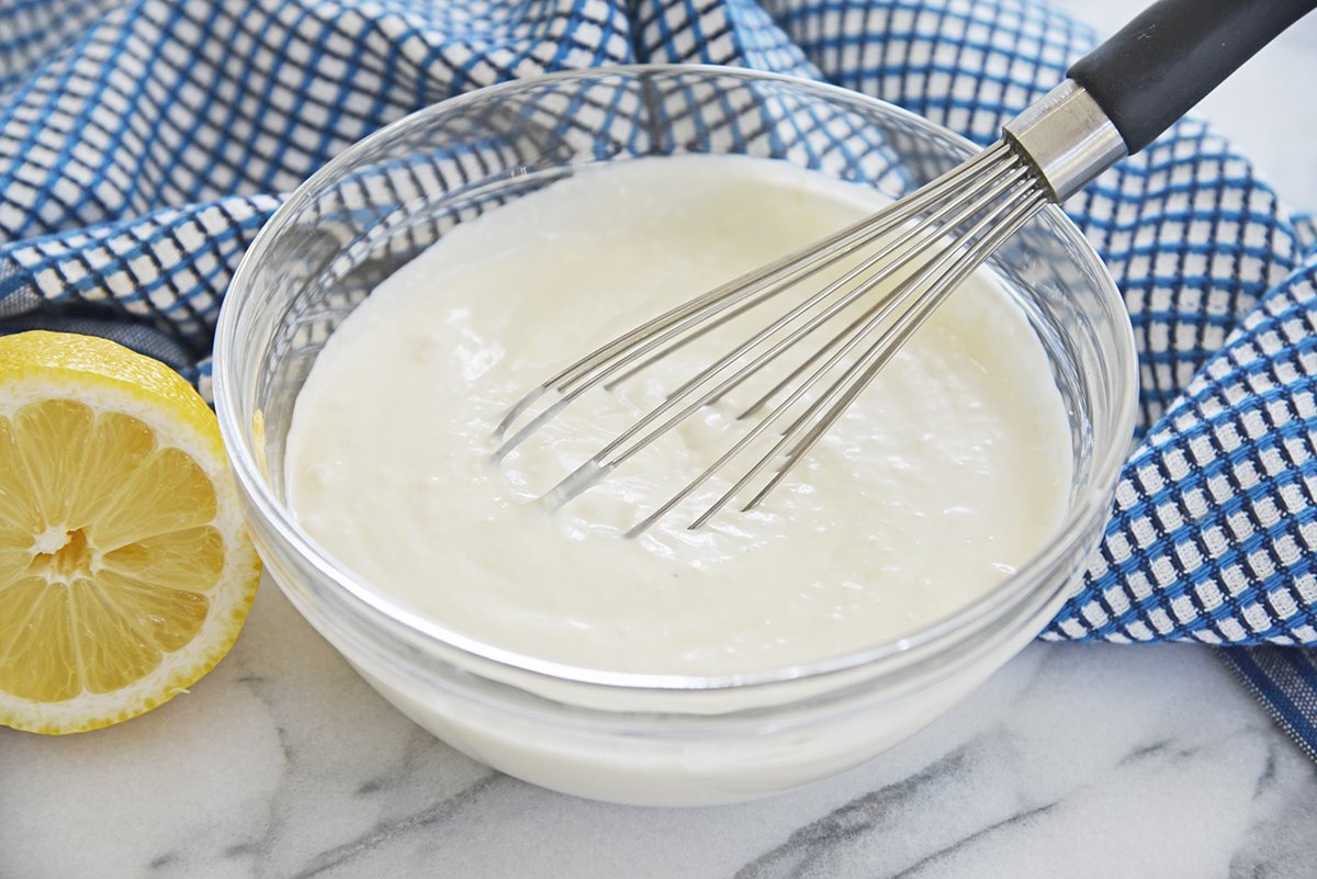 angled shot of whisk in bowl of creamy blue cheese dressing