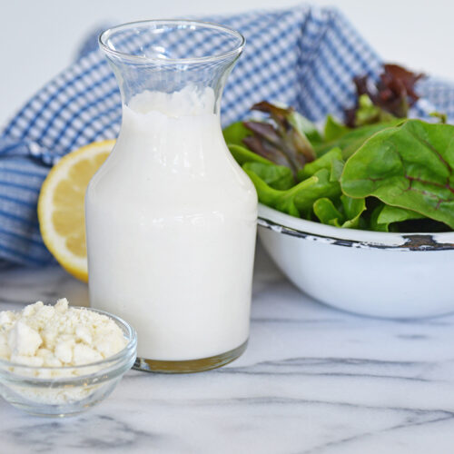 bottle of dressing with bowl of crumbled blue cheese