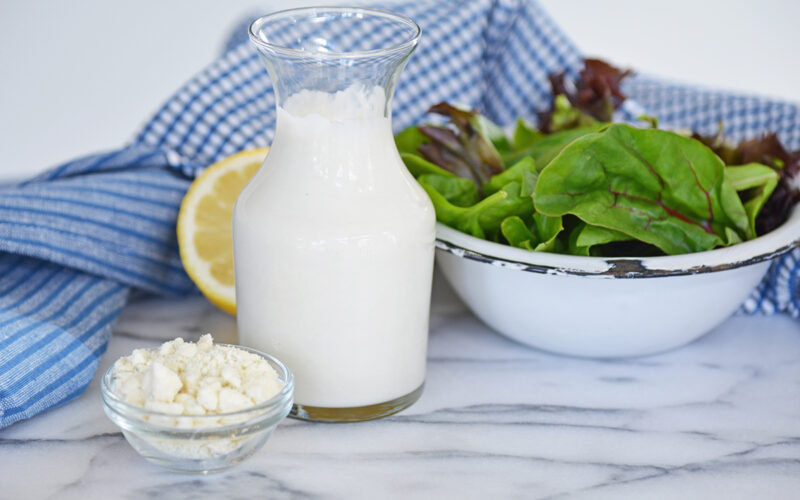 bottle of dressing with bowl of crumbled blue cheese