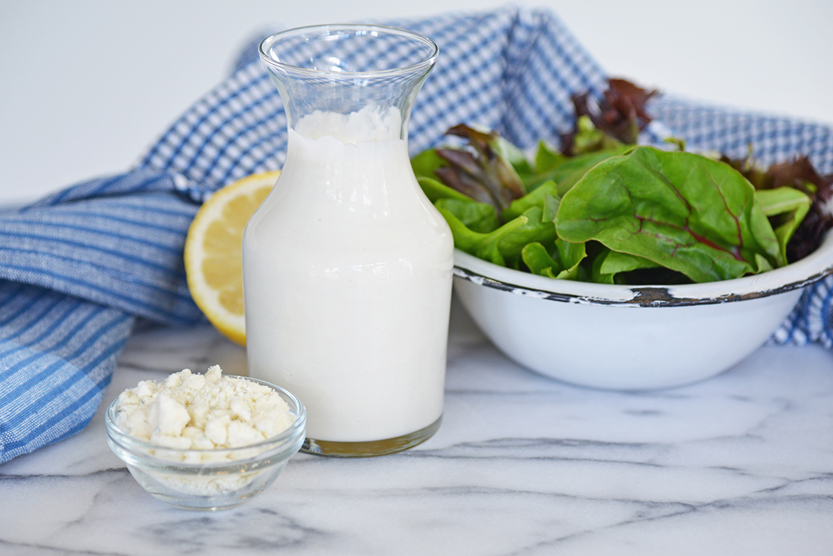 bottle of dressing with bowl of crumbled blue cheese