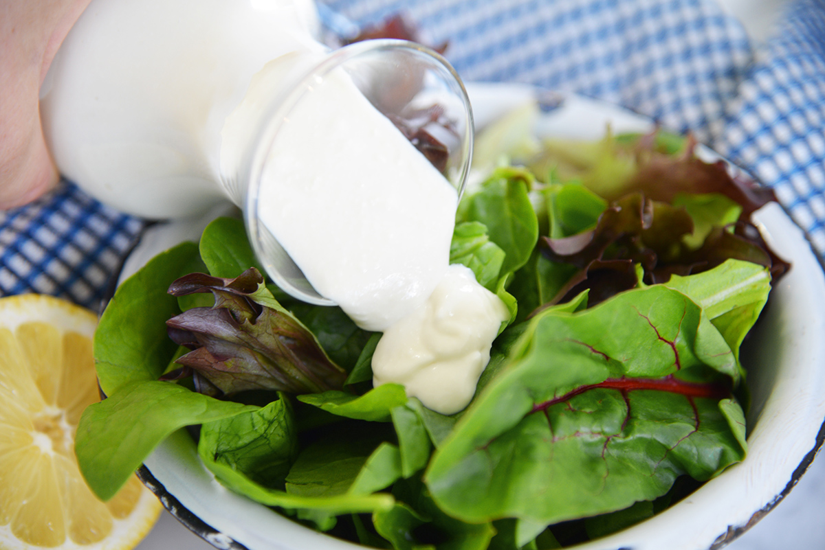 close up of creamy dressing poured onto salad