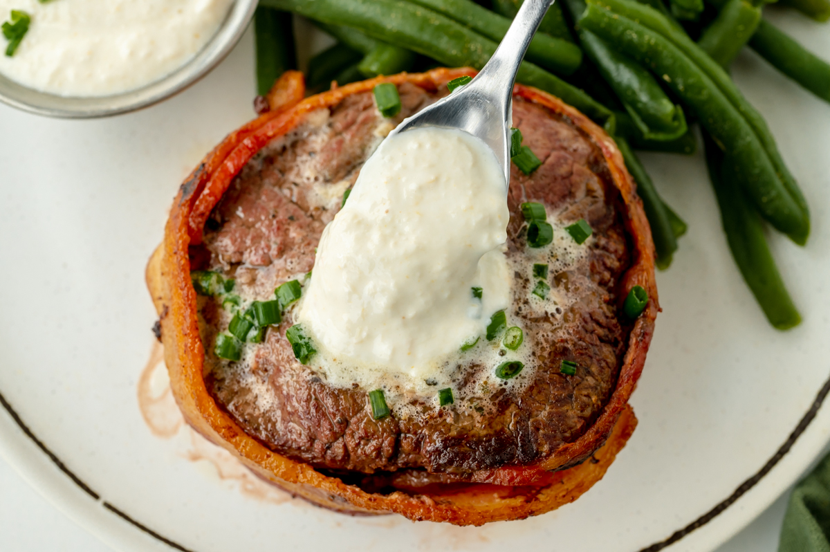 overhead shot of spoon adding horseradish cream sauce to steak