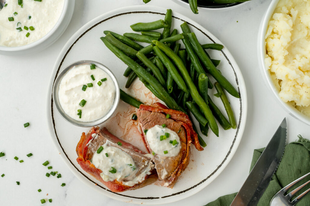 overhead shot of plate of steak and green beans with ramekin of sauce