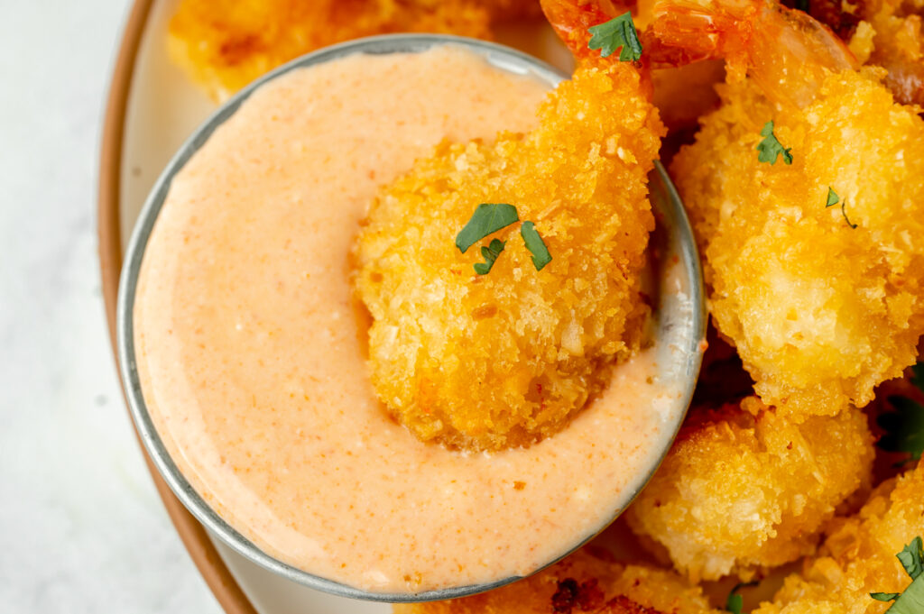 overhead shot of shrimp dipping into red curry sauce