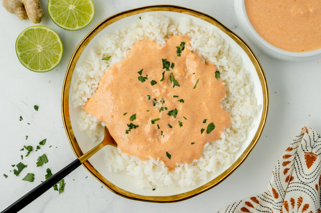 overhead shot of bowl of rice topped with red curry sauce