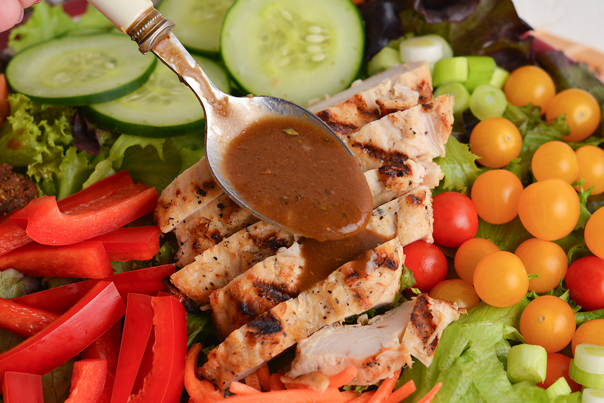 spoon adding dressing to salad