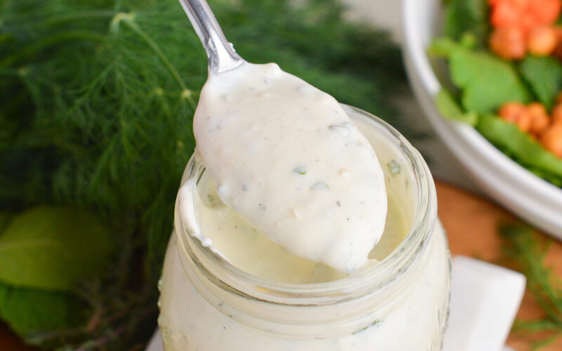 close up of spoon in jar of creamy greek dressing