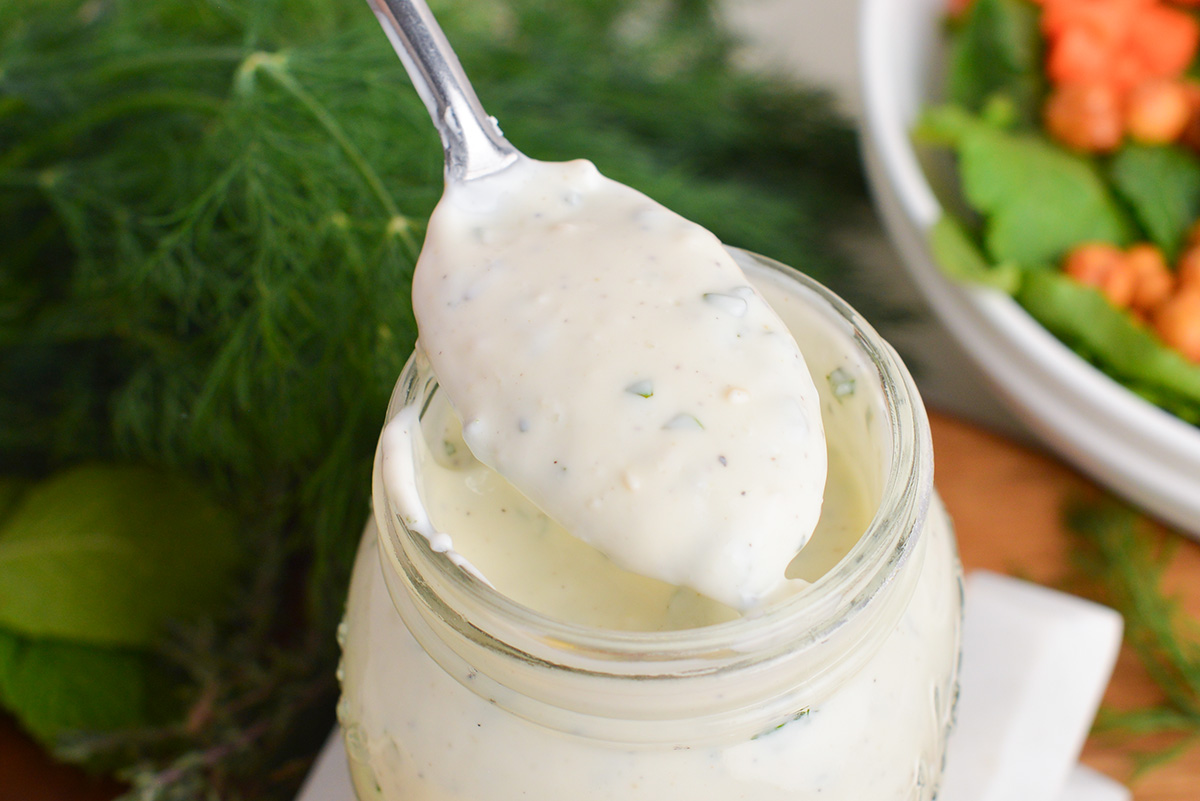 close up of spoon in jar of creamy greek dressing