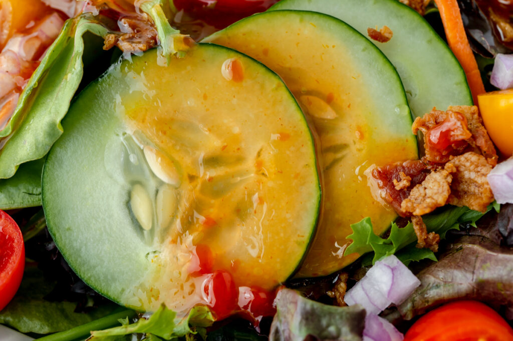 close up of salad dressing over cucumbers