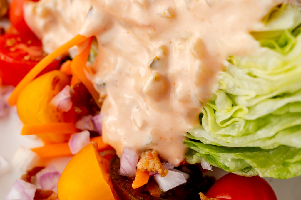 close up angled shot of thousand island dressing on salad