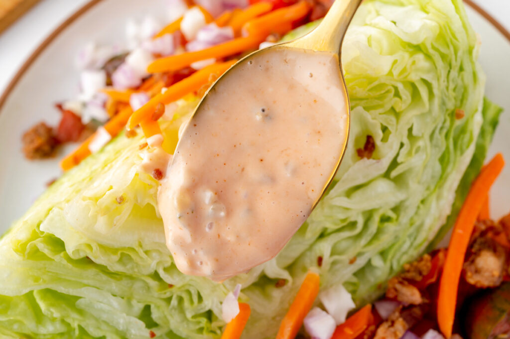 spoon adding dressing to salad