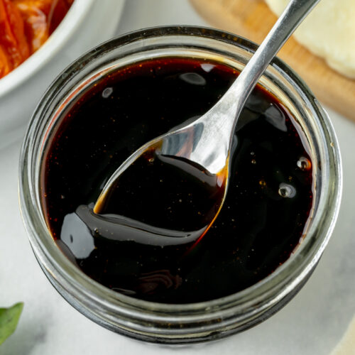 overhead shot of spoon in jar of balsamic reduction sauce