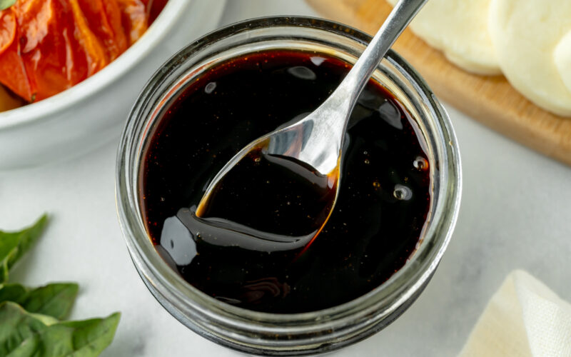 overhead shot of spoon in jar of balsamic reduction sauce