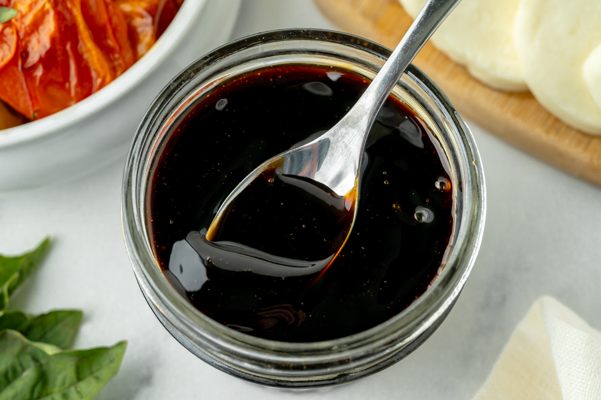 overhead shot of spoon in jar of balsamic reduction sauce