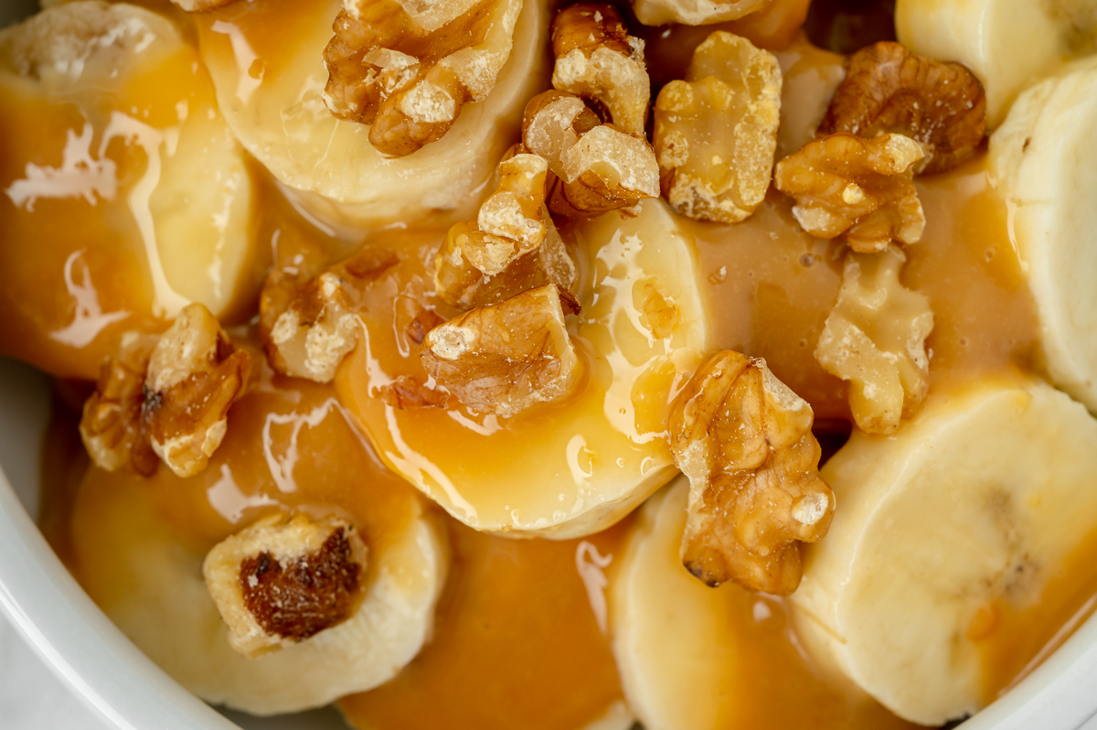 close up overhead shot of bananas topped with walnuts and dulce de leche sauce