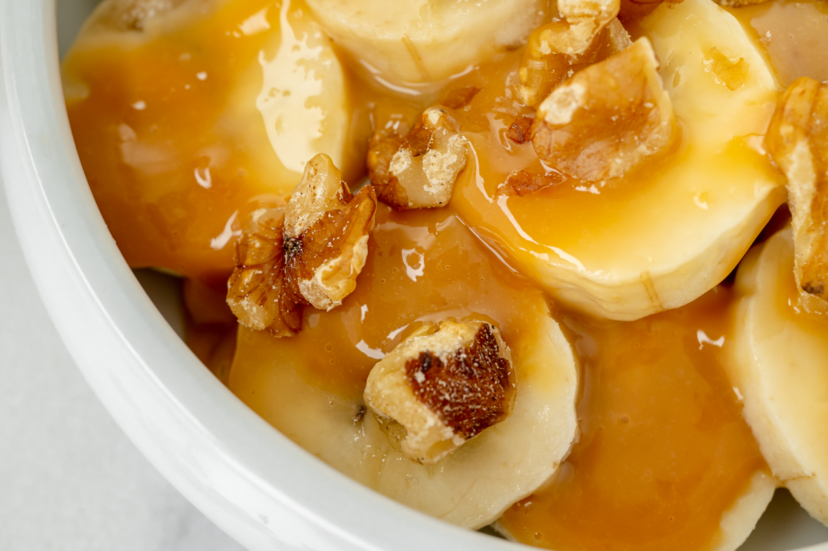 close up overhead shot of bananas topped with walnuts and caramel sauce