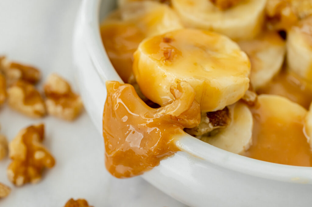 caramel sauce dripping off side of bowl of bananas