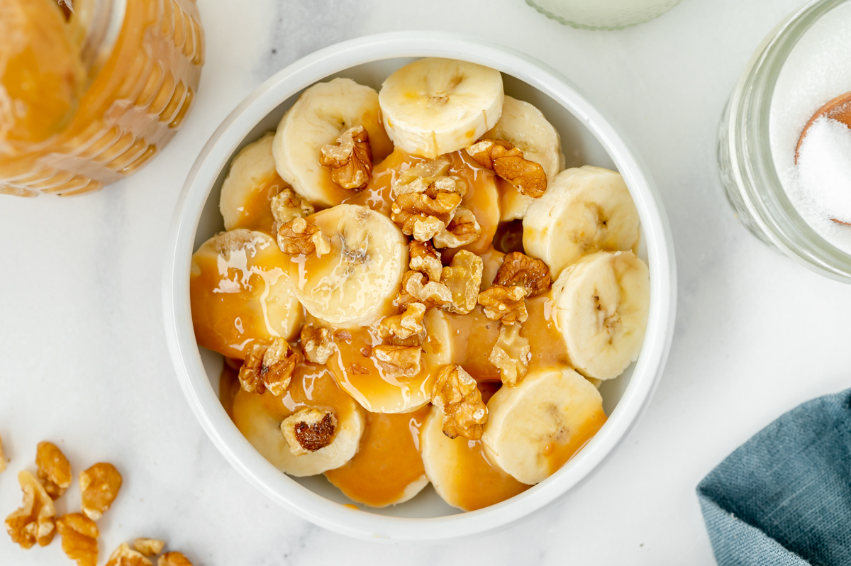 overhead shot of bowl of bananas, walnuts and dulce de leche sauce