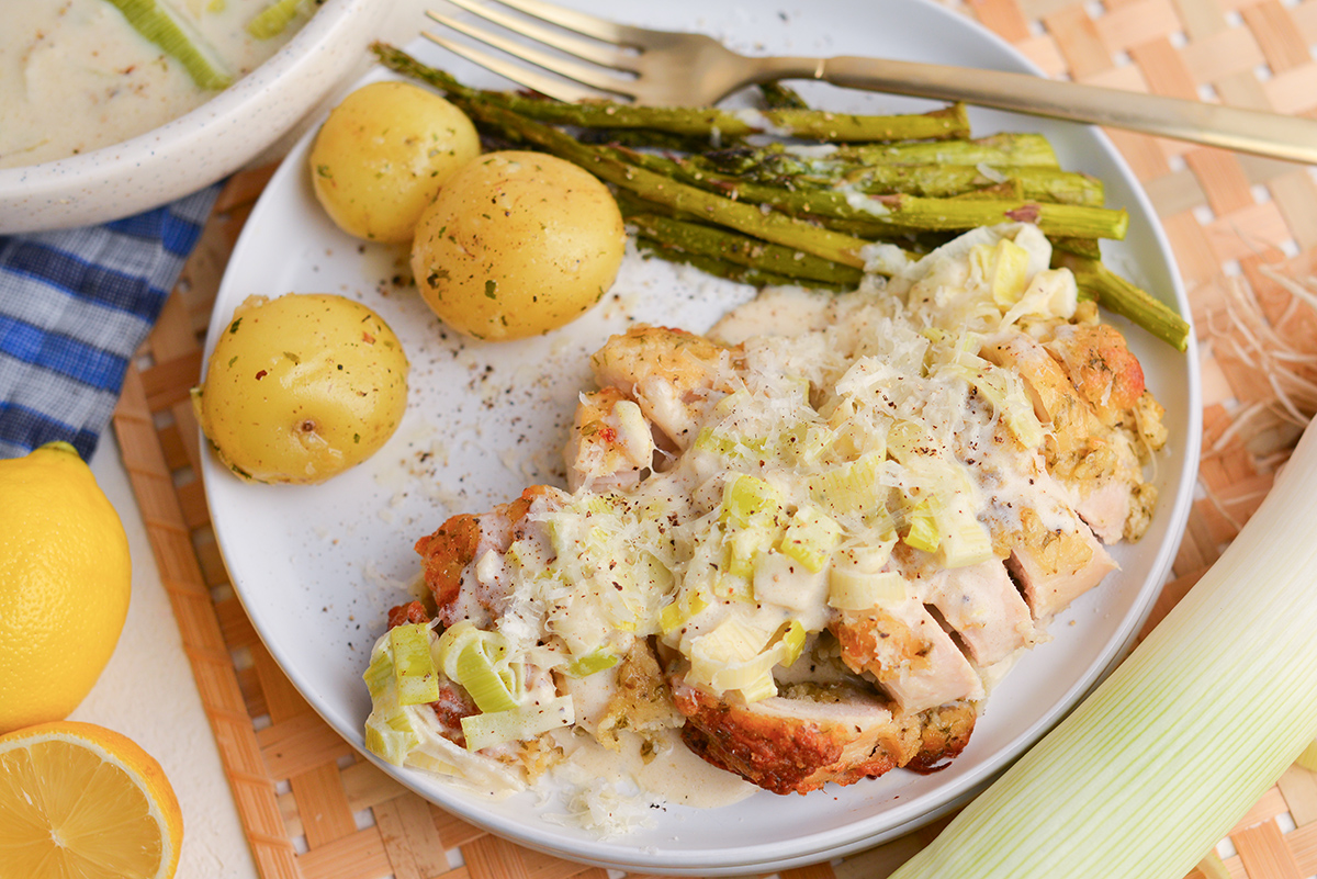 plate of potatoes, asparagus and sliced chicken topped with creamed leeks