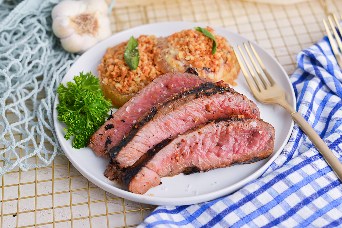 three slices of london broil on plate with onions