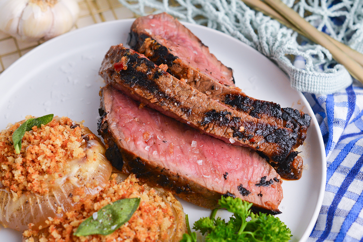 close up of slices of london broil on plate with sides