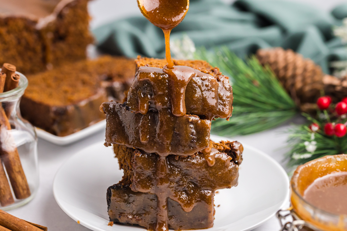 spoon drizzling caramel sauce over stack of cake slices